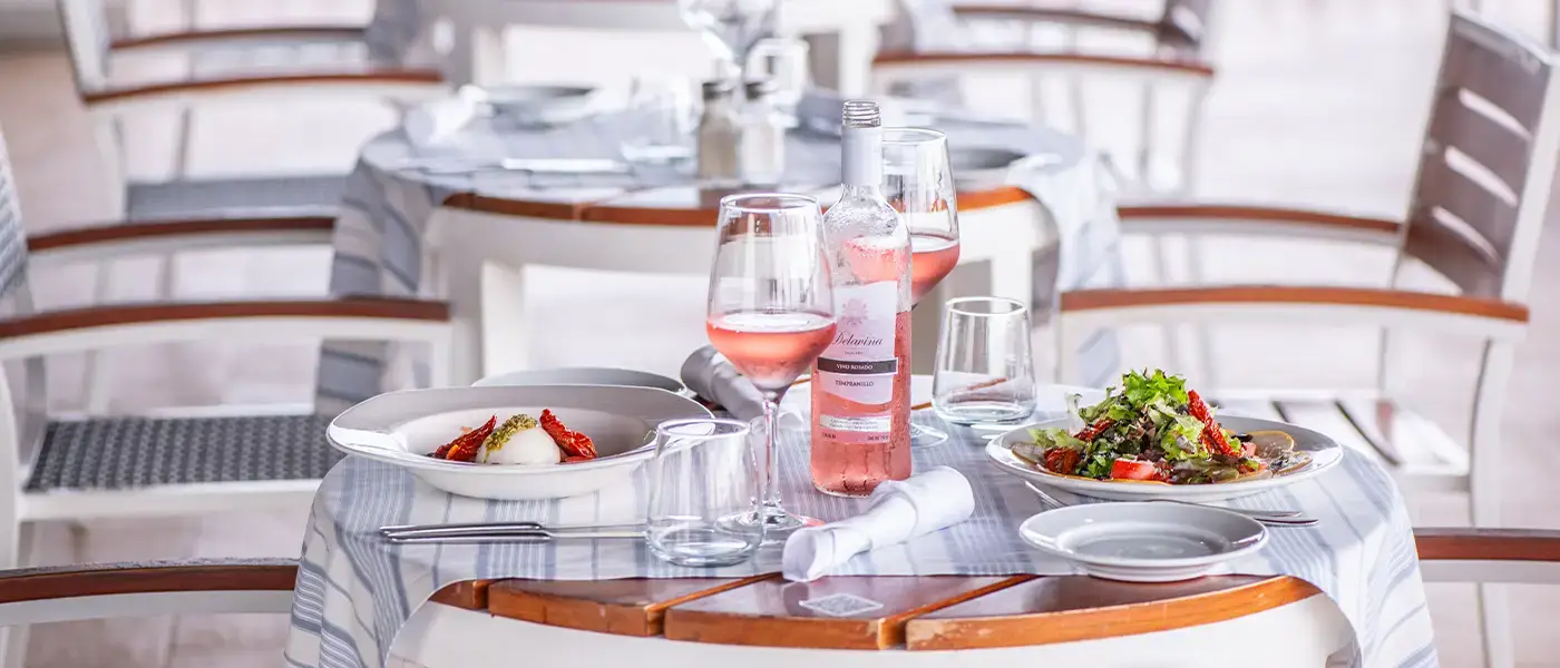 A table laid with food and rosé wine